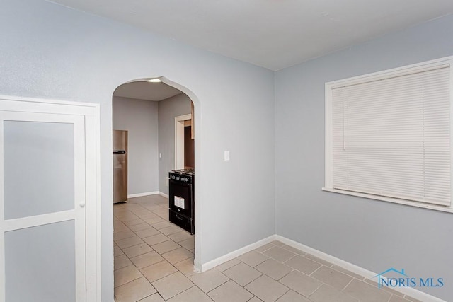 interior space featuring stainless steel fridge, black range with gas stovetop, and light tile patterned floors