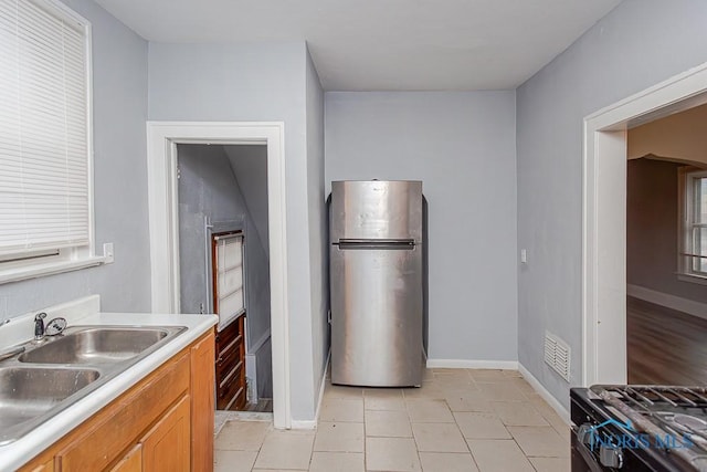 kitchen featuring stainless steel fridge, light tile patterned floors, and sink