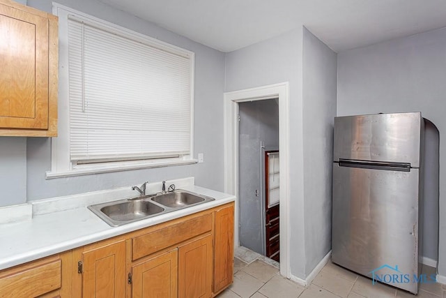 kitchen with stainless steel refrigerator, sink, and light tile patterned floors