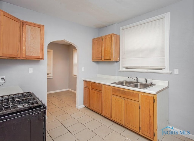 kitchen with light tile patterned flooring, black gas range oven, and sink