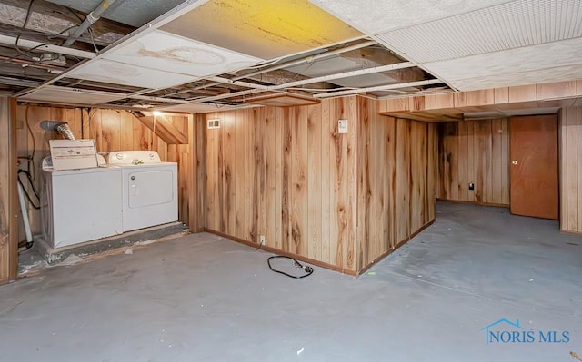 basement featuring wooden walls and independent washer and dryer