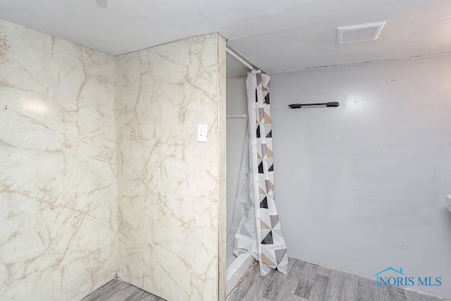 bathroom with hardwood / wood-style flooring and walk in shower