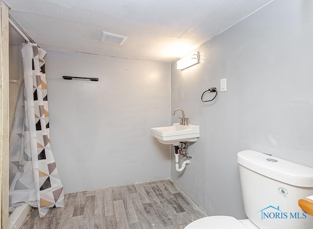 bathroom with hardwood / wood-style floors, a shower with curtain, toilet, and sink