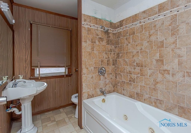 bathroom featuring ornamental molding, toilet, and wooden walls