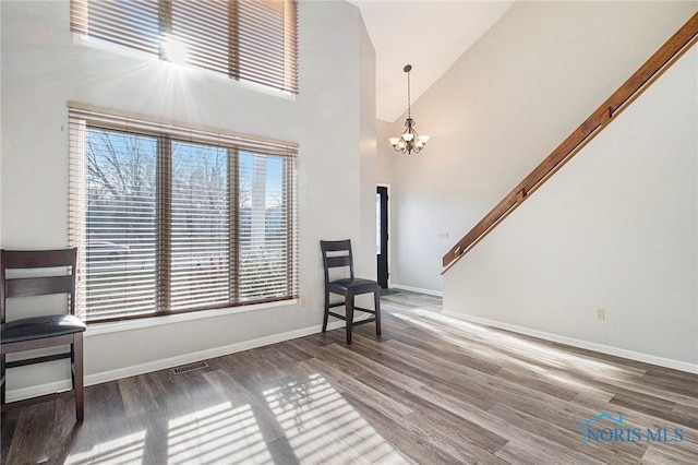 living area with dark wood-type flooring, high vaulted ceiling, and a notable chandelier