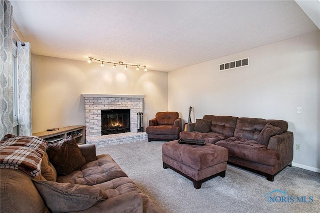 living room featuring carpet flooring, track lighting, and a brick fireplace