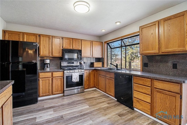 kitchen featuring backsplash, sink, black appliances, and light hardwood / wood-style floors