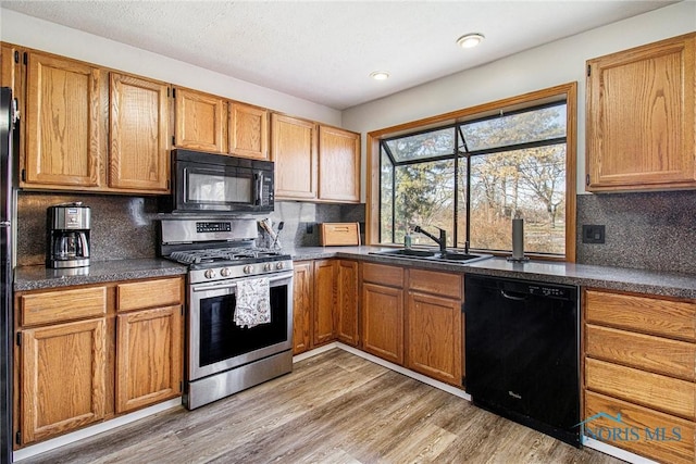 kitchen featuring light wood-type flooring, sink, tasteful backsplash, and black appliances