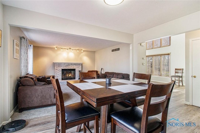 dining area featuring light hardwood / wood-style floors, a fireplace, and track lighting