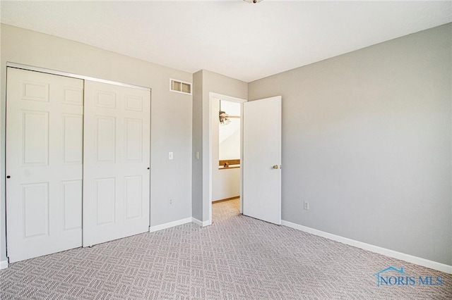 unfurnished bedroom with light colored carpet and a closet