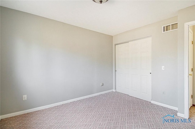 unfurnished bedroom with light colored carpet and a closet