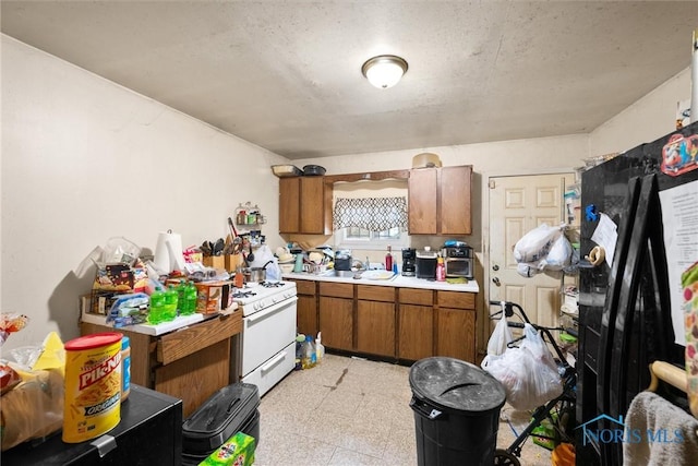 kitchen with a textured ceiling, white gas range, and sink