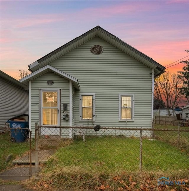 back house at dusk with a lawn