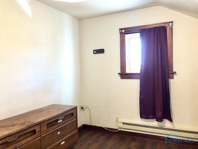 interior space featuring dark hardwood / wood-style floors, vaulted ceiling, and a baseboard heating unit