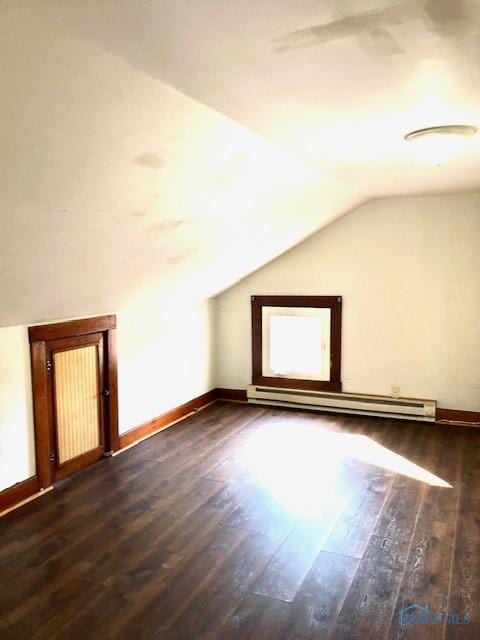 additional living space with baseboard heating, dark wood-type flooring, and vaulted ceiling