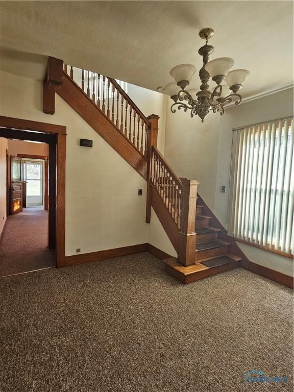 staircase featuring carpet, a chandelier, and beamed ceiling