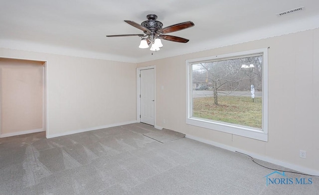 empty room with carpet floors, a wealth of natural light, and ceiling fan