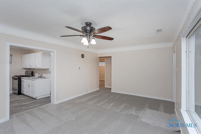 carpeted empty room featuring ceiling fan and sink