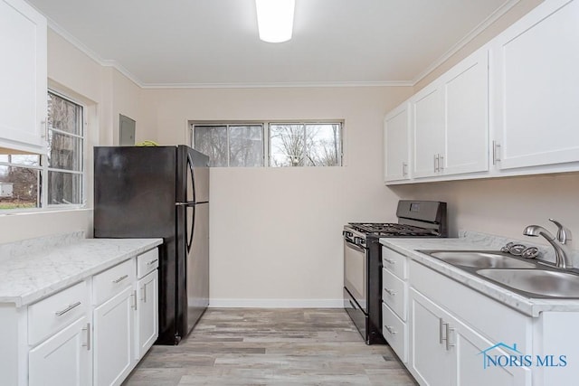 kitchen featuring black appliances, white cabinetry, sink, and a wealth of natural light