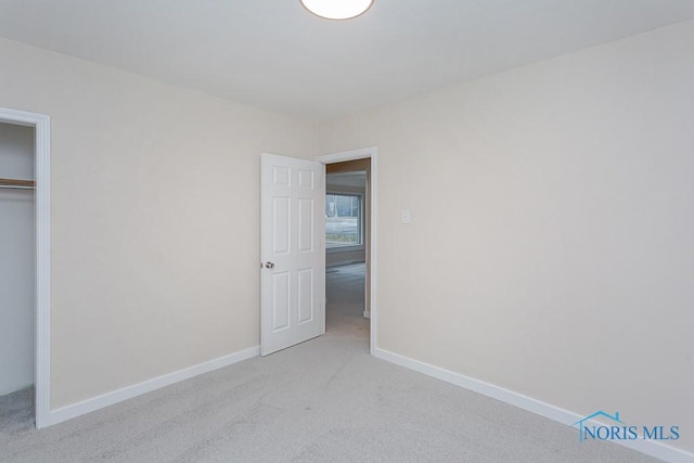 unfurnished bedroom with light carpet and a closet