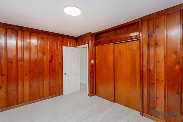 unfurnished bedroom featuring light carpet and wood walls