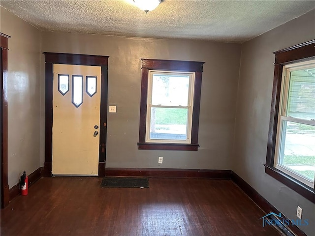 foyer featuring dark wood-type flooring and a textured ceiling