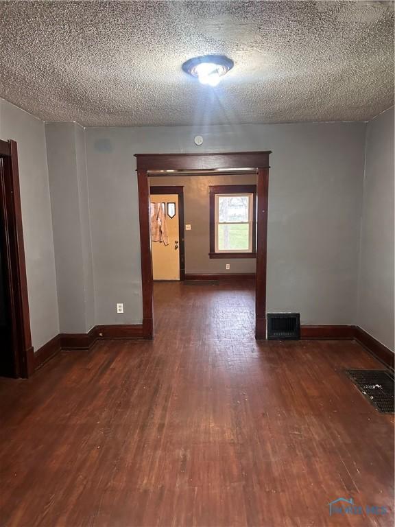 empty room with dark hardwood / wood-style floors and a textured ceiling