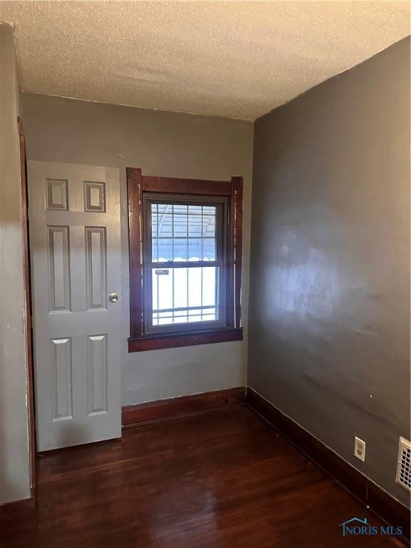 spare room featuring a textured ceiling and dark wood-type flooring