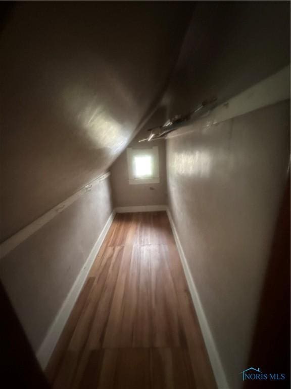 bonus room with hardwood / wood-style floors and vaulted ceiling