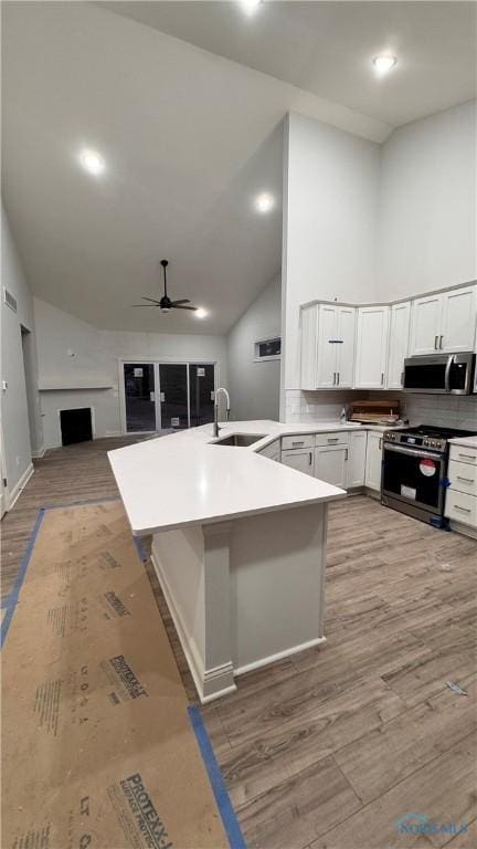 kitchen featuring sink, a breakfast bar area, stainless steel appliances, high vaulted ceiling, and kitchen peninsula