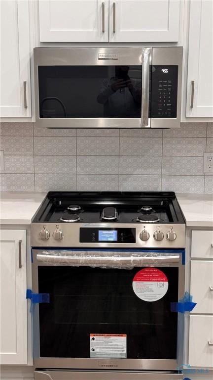 kitchen featuring stainless steel appliances, white cabinetry, and decorative backsplash