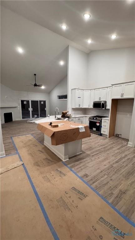 kitchen featuring light hardwood / wood-style flooring, high vaulted ceiling, white cabinets, and appliances with stainless steel finishes