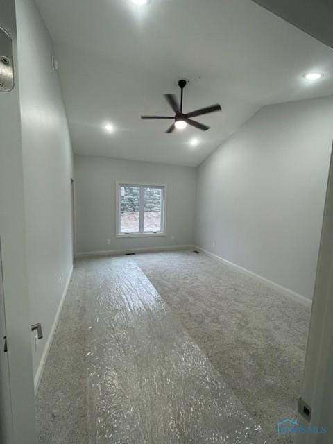 empty room with lofted ceiling, ceiling fan, and baseboards