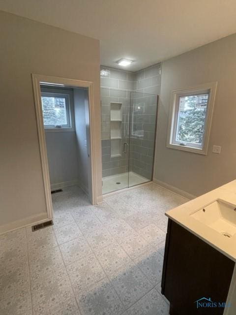 full bathroom with plenty of natural light, a shower stall, visible vents, and baseboards