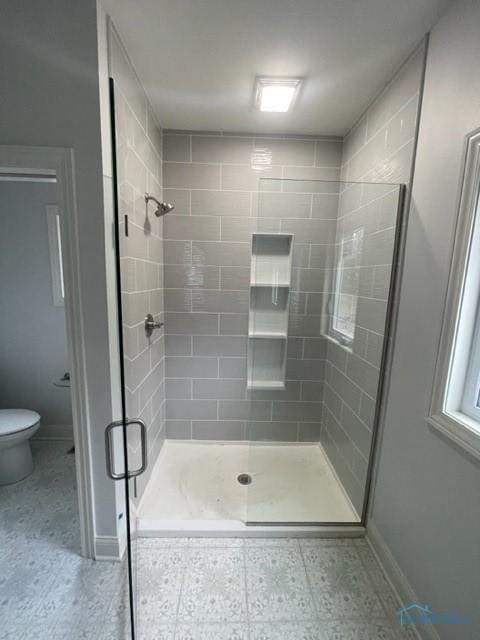 bathroom featuring toilet, a stall shower, and baseboards