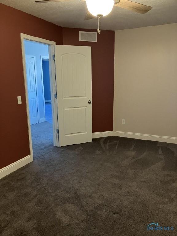 unfurnished room with dark colored carpet