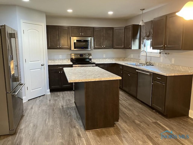 kitchen featuring pendant lighting, dark wood-type flooring, sink, a kitchen island, and stainless steel appliances