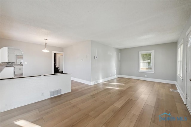 unfurnished living room with a textured ceiling and light wood-type flooring