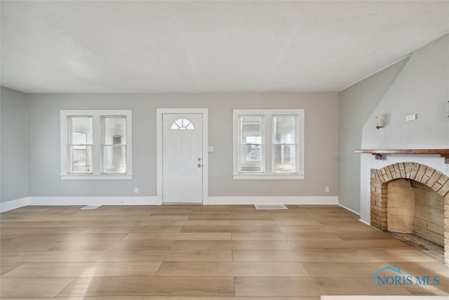 foyer entrance with a textured ceiling, light hardwood / wood-style floors, and a fireplace