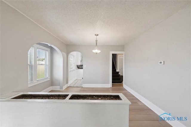 interior space featuring a textured ceiling, wood-type flooring, and decorative light fixtures