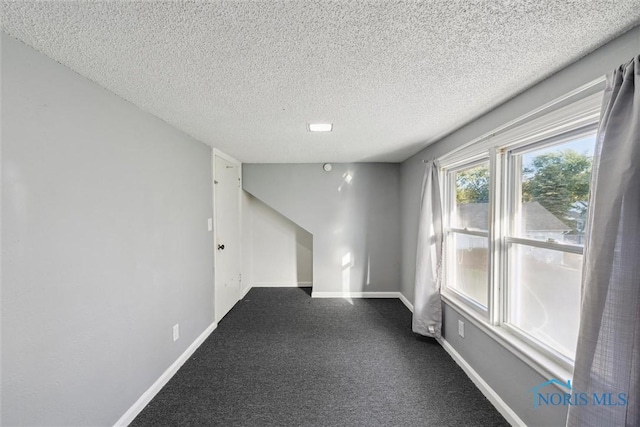 unfurnished room with carpet and a textured ceiling