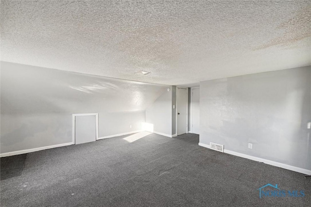 carpeted empty room featuring lofted ceiling and a textured ceiling