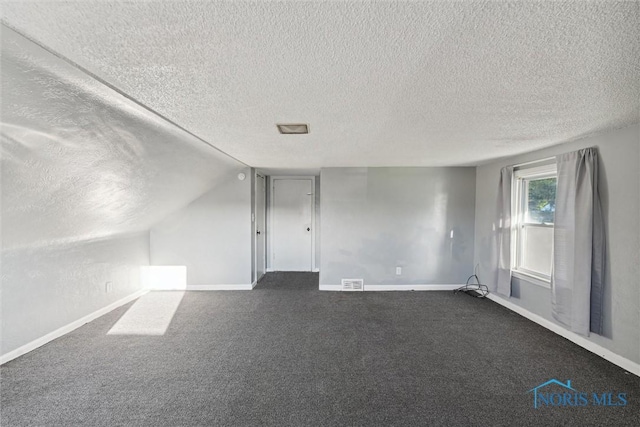 bonus room with a textured ceiling, dark carpet, and lofted ceiling