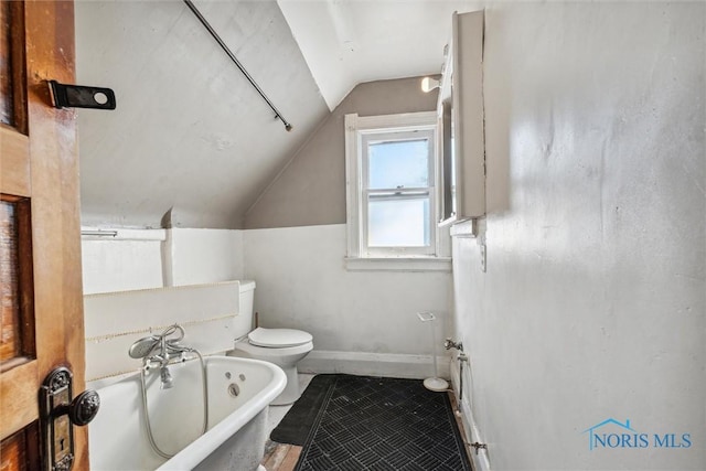 bathroom with tile patterned floors, toilet, lofted ceiling, and a tub