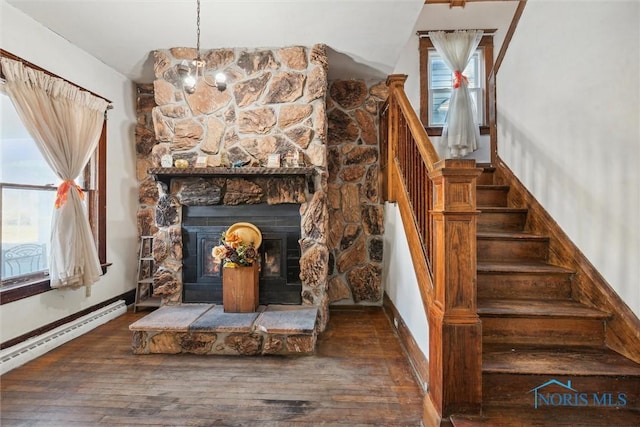 stairs with hardwood / wood-style flooring, a notable chandelier, a fireplace, and a baseboard heating unit