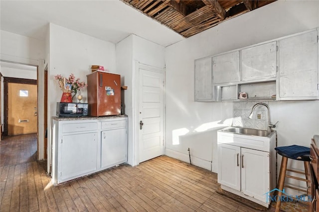 kitchen with white cabinetry, sink, and light wood-type flooring