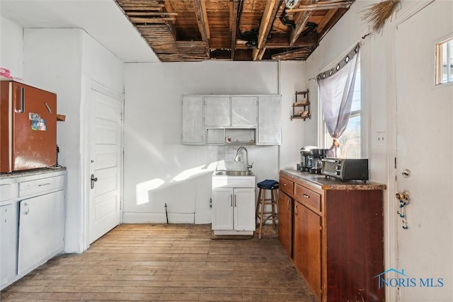 kitchen featuring white cabinets, plenty of natural light, light hardwood / wood-style floors, and sink