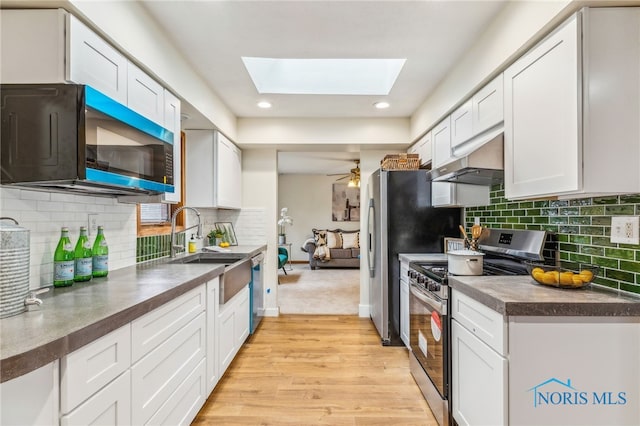 kitchen featuring white cabinets, stainless steel appliances, light hardwood / wood-style flooring, and a skylight