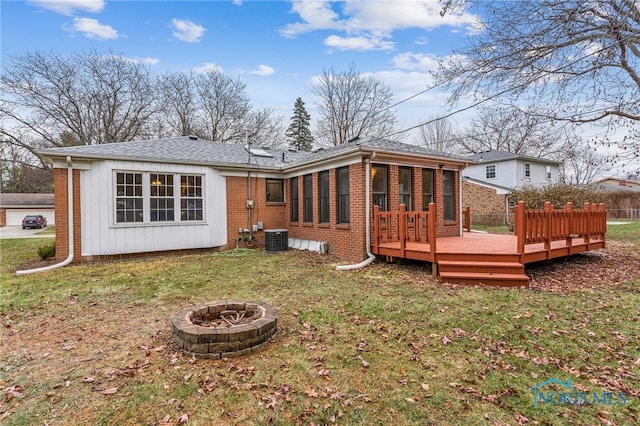 back of property featuring a fire pit, cooling unit, a deck, and a yard