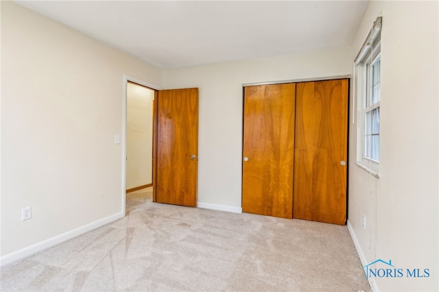 unfurnished bedroom with light carpet and a closet